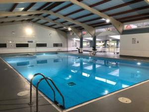 a large swimming pool with blue water in a building at Chalet Thirtyone in Deal