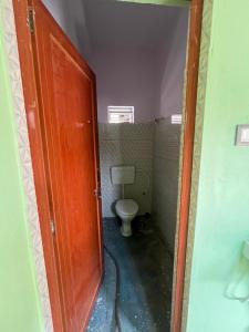a bathroom with a toilet and a wooden door at Radhashyam in Durgāpur