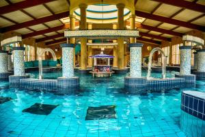 a large swimming pool in a hotel with a large building at Ala'Toboz Siófok in Siófok
