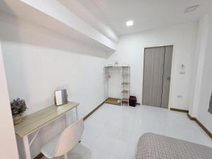 a white room with a desk and a door at Huggdaily 7 in Ban Khlong Thewa