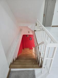 a staircase with a red wall and a red door at Huggdaily 7 in Ban Khlong Thewa