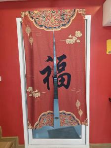 a curtain with chinese writing on a red wall at Huggdaily 7 in Ban Khlong Thewa