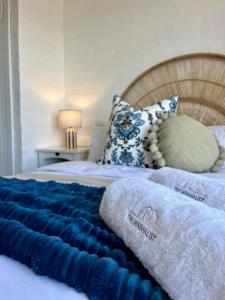 a bed with a blue blanket and pillows on it at Endless blue ocean view escape in Langebaan