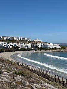 a beach with people swimming in the water at Endless blue ocean view escape in Langebaan