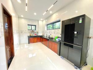 a kitchen with a black refrigerator and wooden cabinets at KIMO HOUSE Khem Beach in Phú Quốc