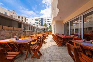 a row of wooden tables and chairs in a restaurant at Apart-Hotel Saraj in Dobra Voda
