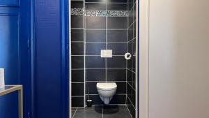 a bathroom with a toilet in a black tiled wall at Cocon de Charme - T2 sur Place d'Armes in Valenciennes