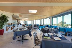 a restaurant with blue tables and chairs and windows at Brit Hotel Golfhotel Saint Samson in Pleumeur-Bodou