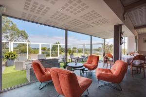 a room with orange chairs and tables and windows at Brit Hotel Golfhotel Saint Samson in Pleumeur-Bodou