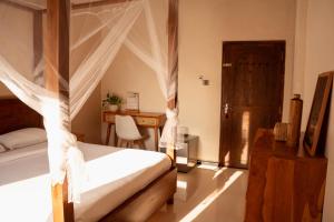 a bedroom with a canopy bed and a desk at Bakamuna Villa in Dickwella