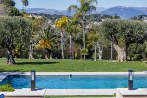 a swimming pool in a park with palm trees at REF 2193 - Super Cannes Villa for rent in Vallauris