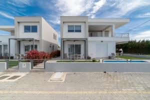 a white house with a pool in front of it at Thalassa & Thalassa Prive Residential Complex in Ofrínion