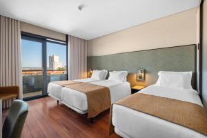 a hotel room with two beds and a window at Axis Porto Business & Spa Hotel in Porto