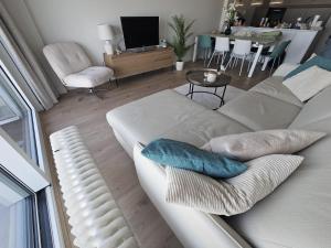 a living room with a white couch with pillows on it at Isola Bella - Luxe Verblijf op de Zeedijk met Panoramisch Uitzicht in Blankenberge