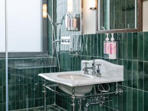 a green tiled bathroom with a sink and a mirror at Numa Berlin Potsdamer Platz in Berlin