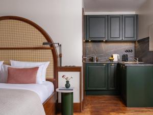 a bedroom with a bed and a kitchen with green cabinets at Numa Berlin Potsdamer Platz in Berlin