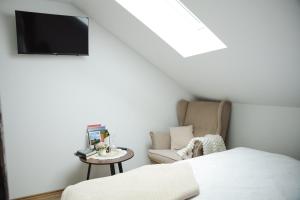 a bedroom with a bed and a chair and a tv at VALLIS sobe in Požega