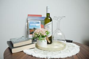 a table with books a bottle of wine and a vase with flowers at VALLIS sobe in Požega