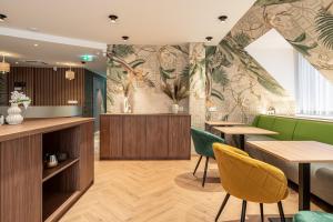 a restaurant with wooden tables and green chairs at Dolce Vita Hotel Art in Budapest