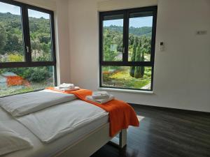 a bedroom with a bed with an orange blanket and two windows at Korcula Holiday in Korčula +72 photos
