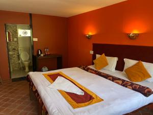 a bedroom with a large bed with orange walls at Dakshinkali & Dollu Resort in Pharping +3 photos