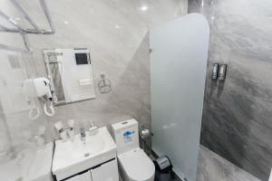 a white bathroom with a toilet and a sink at Classic Hotel Samarkand in Samarkand