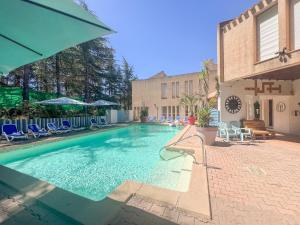 a swimming pool with blue chairs and a building at Résidence Torre Del Far in Tautavel