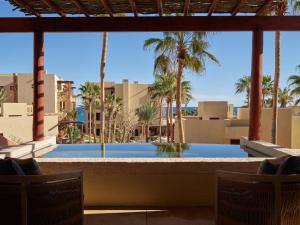 a view of a pool with palm trees and buildings at Waldorf Astoria Los Cabos Pedregal in Cabo San Lucas