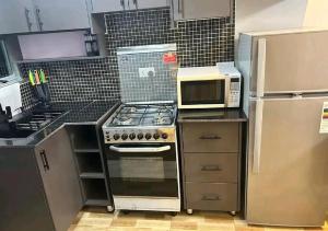a kitchen with a stove top oven next to a microwave at KiGALI CITY COMFORT ACCOMMODATION in Kigali