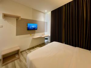a bedroom with a bed and a tv on the wall at Oemah Djari Hotel Syariah Salatiga in Salatiga