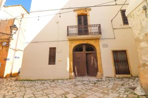 a white building with a brown door and a balcony at Penelope's House in Otranto in Otranto