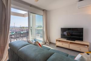 a living room with a blue couch and a large window at AT Ponent II B3 in Oliva