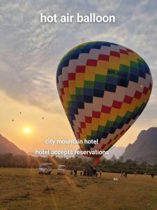 a hot air balloon is flying over a field at city mountain hotle in Vang Vieng