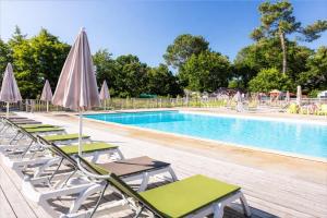 a swimming pool with lounge chairs and umbrellas at bungalow le TXOKO in Lit-et-Mixe