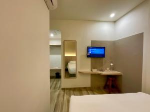 a room with a bed and a desk with a television at Oemah Djari Hotel Syariah Salatiga in Salatiga