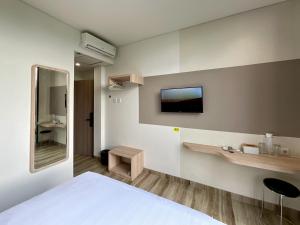 a bedroom with a bed and a tv on the wall at Oemah Djari Hotel Syariah Salatiga in Salatiga