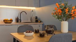 a dining room table with a vase of orange flowers at Antresola - Apartamenty Parkowe in Gniezno