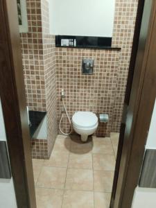a bathroom with a toilet in a tiled room at Hotel Sepoy Grande in Mysore