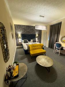 a hotel room with a bed and a yellow couch at Royal Sportsman Hotel in Porthmadog