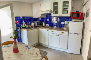 a small kitchen with white cabinets and a white refrigerator at Gîte Le Parigney, proche de la voie bleue in Igney