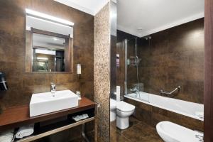a bathroom with a sink and a toilet and a mirror at Axis Porto Business & Spa Hotel in Porto +37 photos