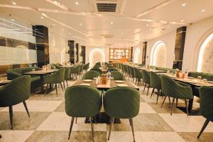 a dining room with tables and green chairs at Madhuram Hotel in Ayodhya