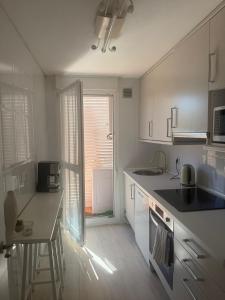 a kitchen with white cabinets and a table and a window at El Rincón de Usgo in Miengo