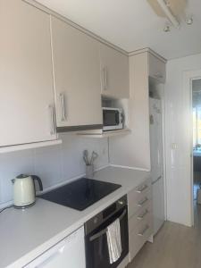a kitchen with white cabinets and a microwave at El Rincón de Usgo in Miengo +25 photos