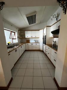 a kitchen with white cabinets and a tile floor at Let Us accommodation in East London