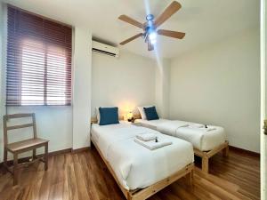 two beds in a room with a ceiling fan at GATU City Puerto Preferente mayores 21 años y familias in El Puerto de Santa María