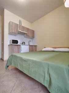 a bedroom with a large green bed and a kitchen at Orange Guest Rooms in Odesa