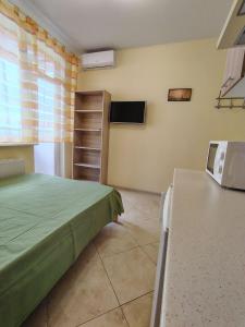 a bedroom with a green bed and a television at Orange Guest Rooms in Odesa