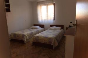 two beds in a small room with a window at Apartments Daidzic by El-Pi Tours in Njivice