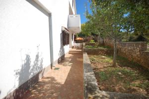 a walkway next to a white building with a tree at Apartments Daidzic by El-Pi Tours in Njivice